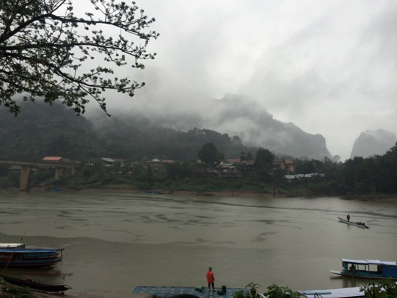 Rainy dock with boats around it.