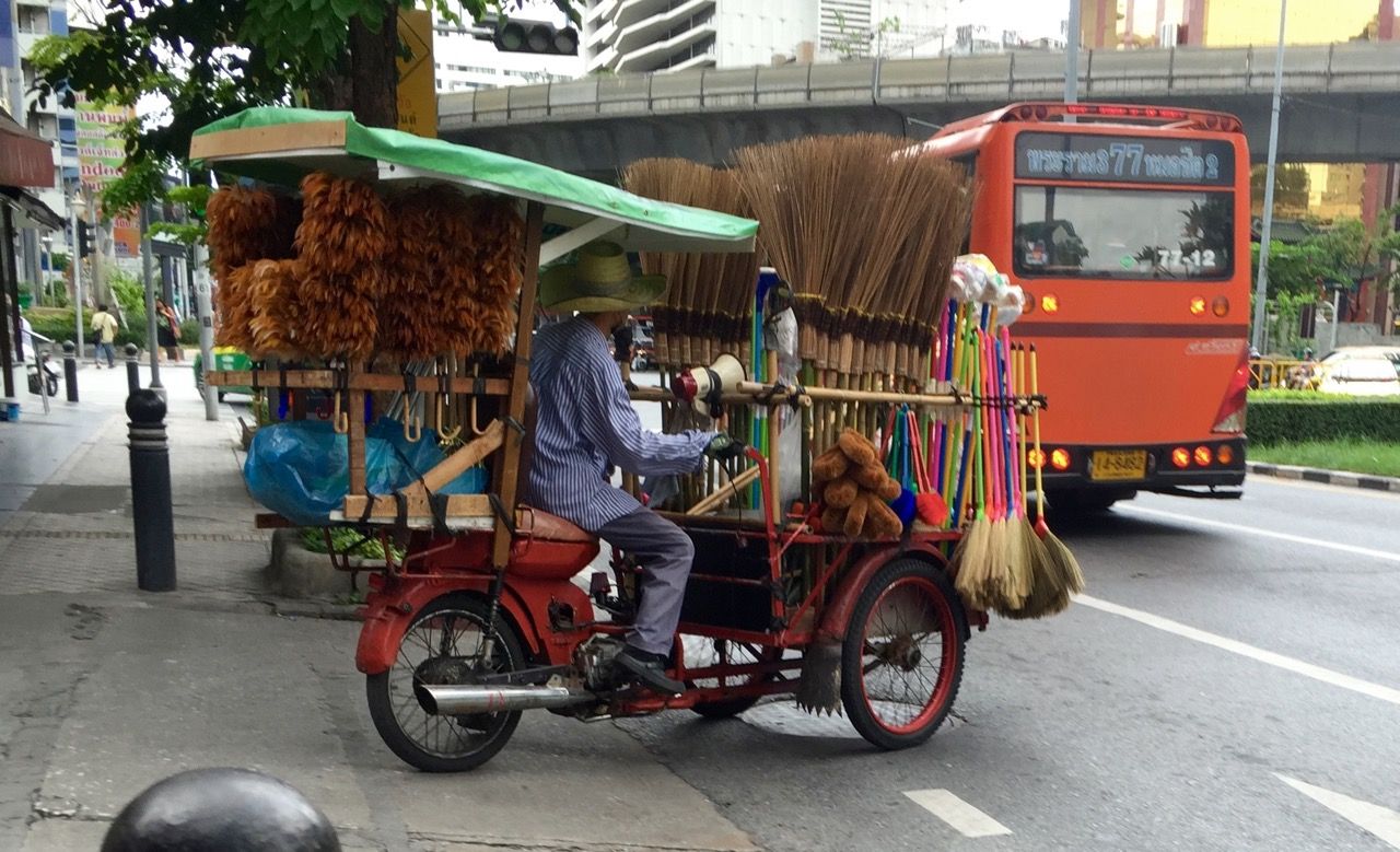 A man driving a cart of brooms.
