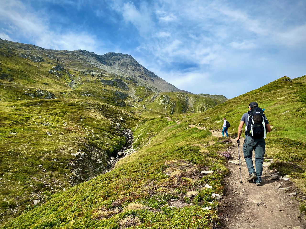 Two men hiking upwards in the hills toward a distant mountain.