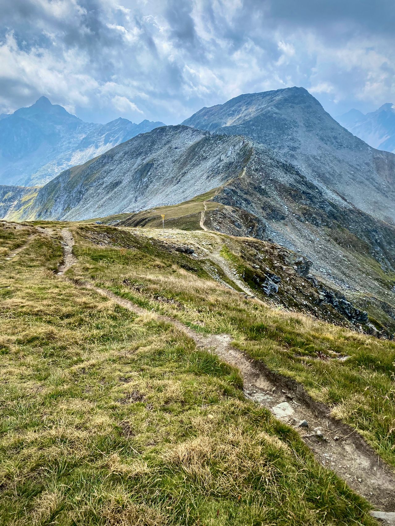 A trail visible along a ridge leading upward toward mountain peaks.