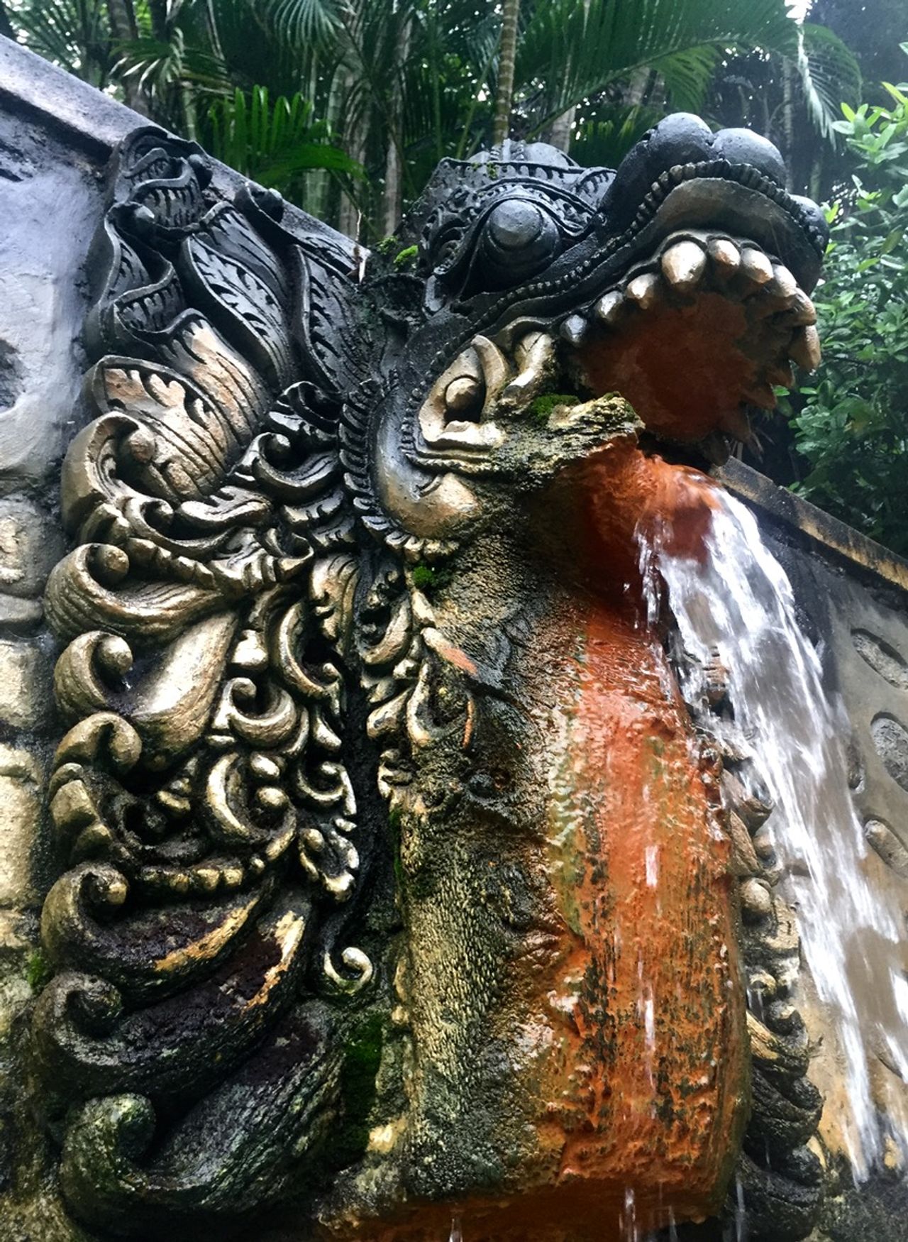 An ornate stone carving of a dragon with water flowing out of the mouth.