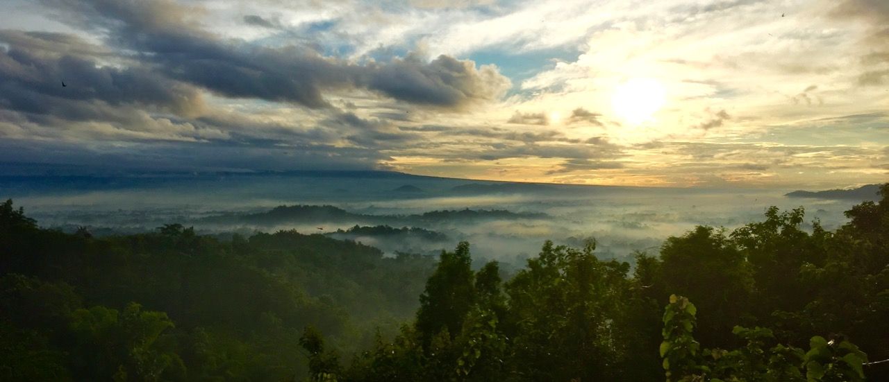 Cloud-filled sky at sun rise with mist drifting over the mountains.