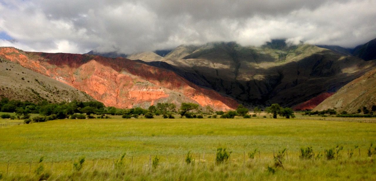 Cumulus clouds hovering over a mountain made of red rock.