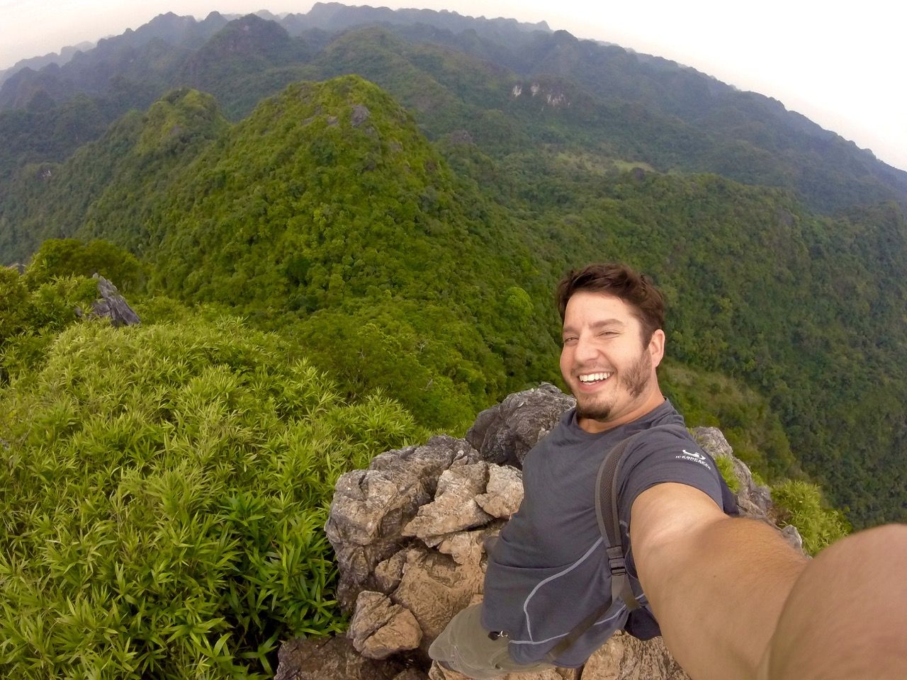 Man smiling into camera while standing on a mountain.