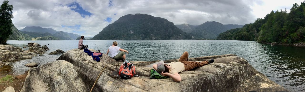 People lounging on rocks at the edge of a lake.