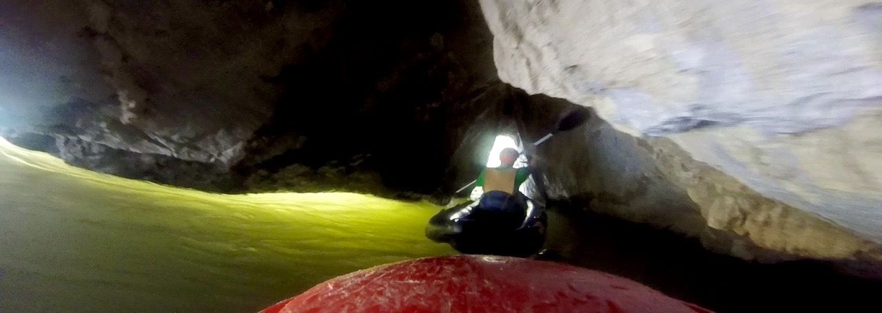 Man kayaking through a small cave.