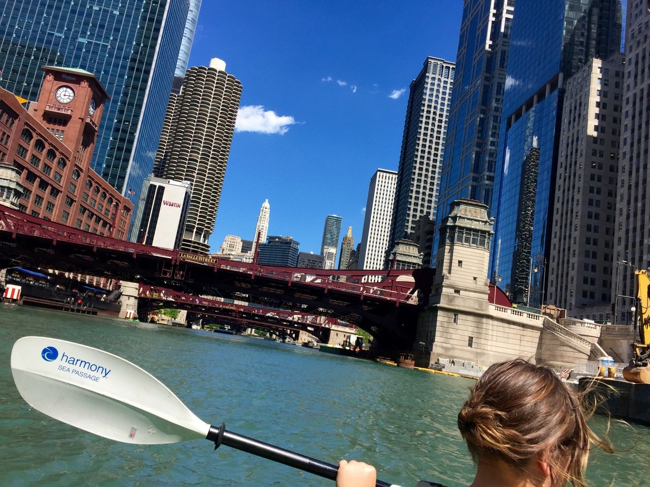 Woman paddline kayak in the Chicago river as they pass Marina Towers.