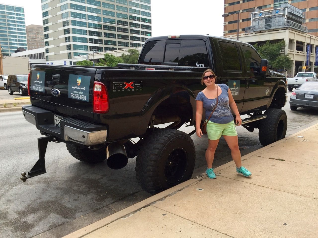 Woman posing in front of large pickup truck.
