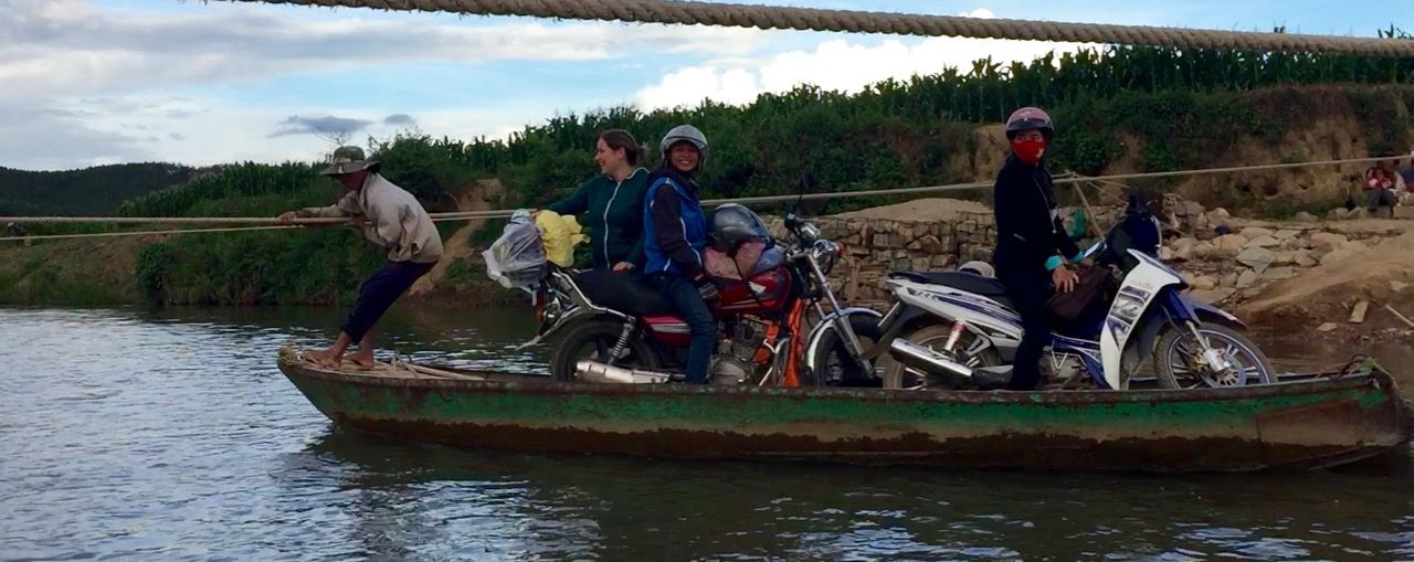 People riding a hand-pulled boat across a river.