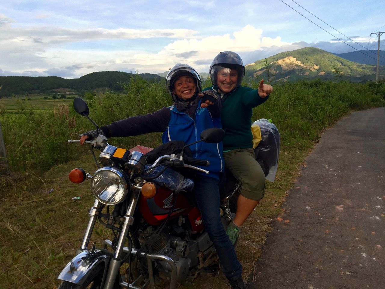 Two people waving while sitting on a motorbike.