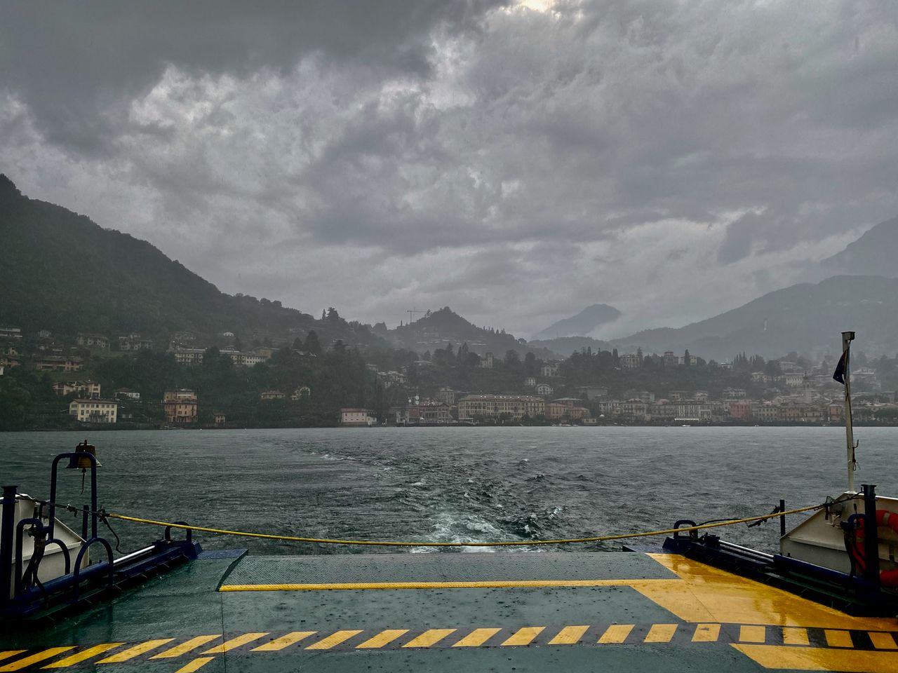 A cloudy, overcast view of Menaggio from the back of a ferry.