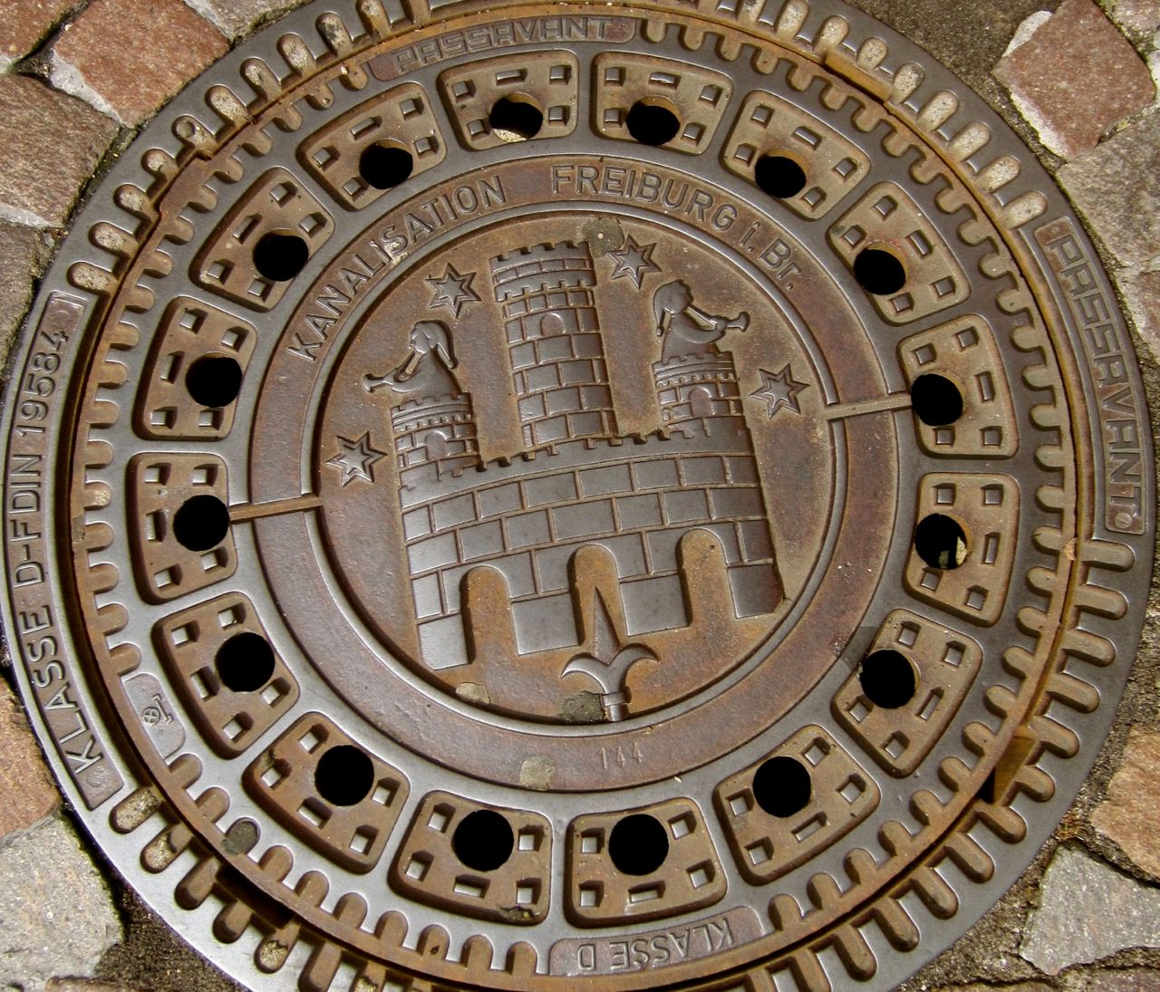 A manhole cover with elaborate artwork of a castle.