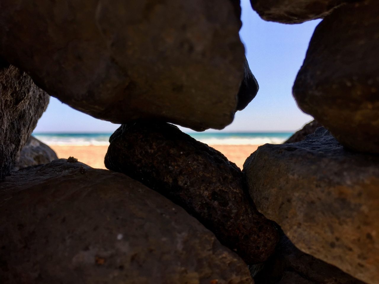Peeking through the holes in a pile of rocks at the beach.
