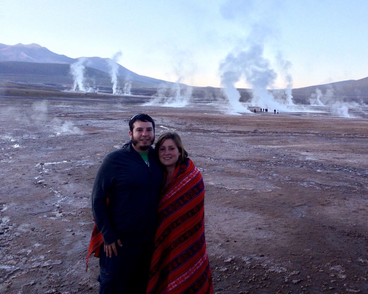 A couple standing in the main field of Geysers del Tatio