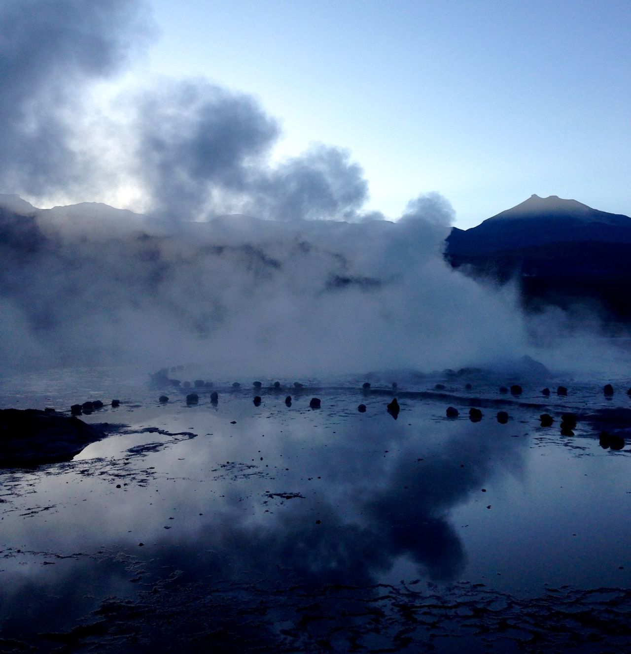 A geyser spewing steam before sunrise.