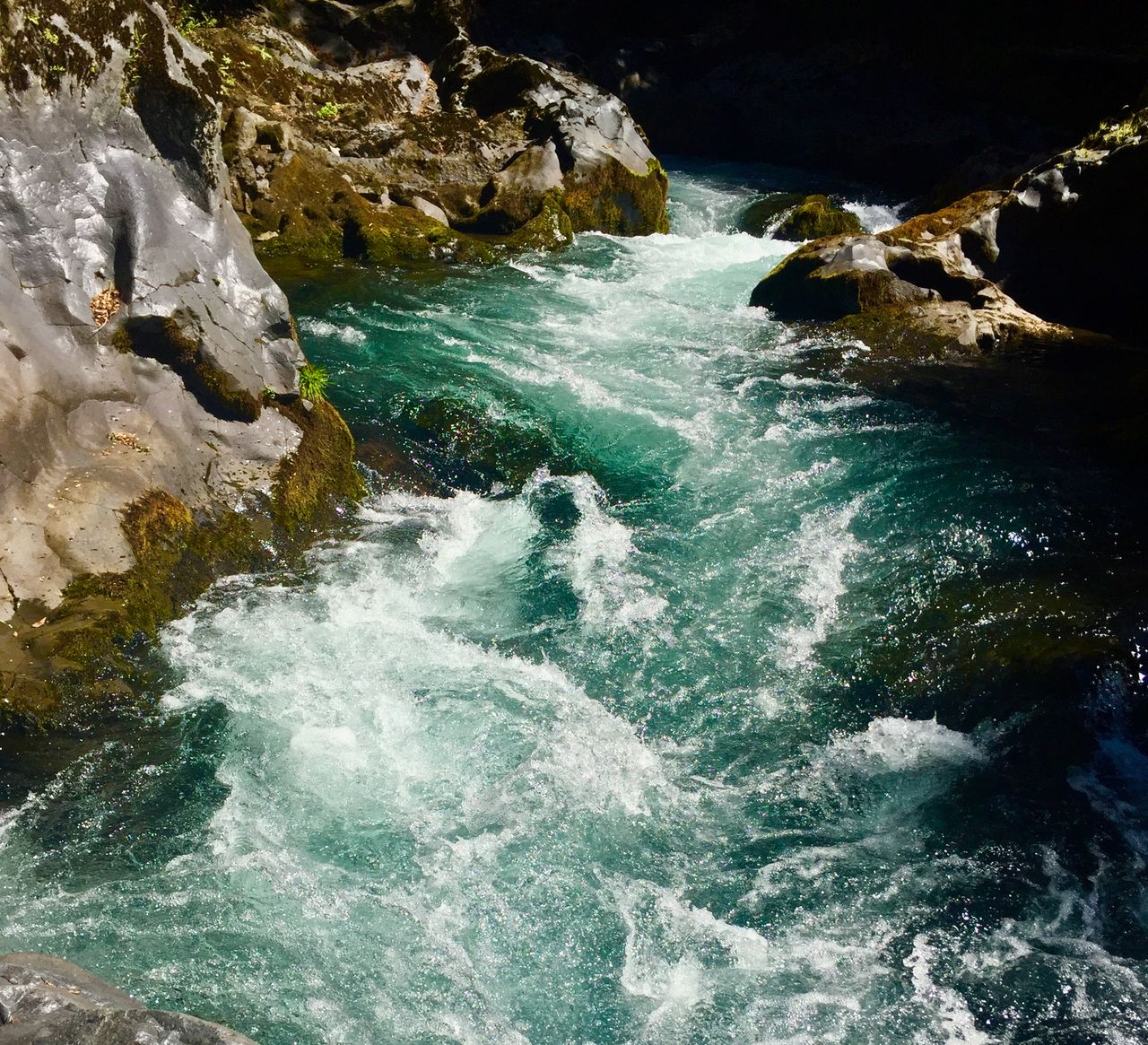 Greenish waterfalls tumbling over rocks.