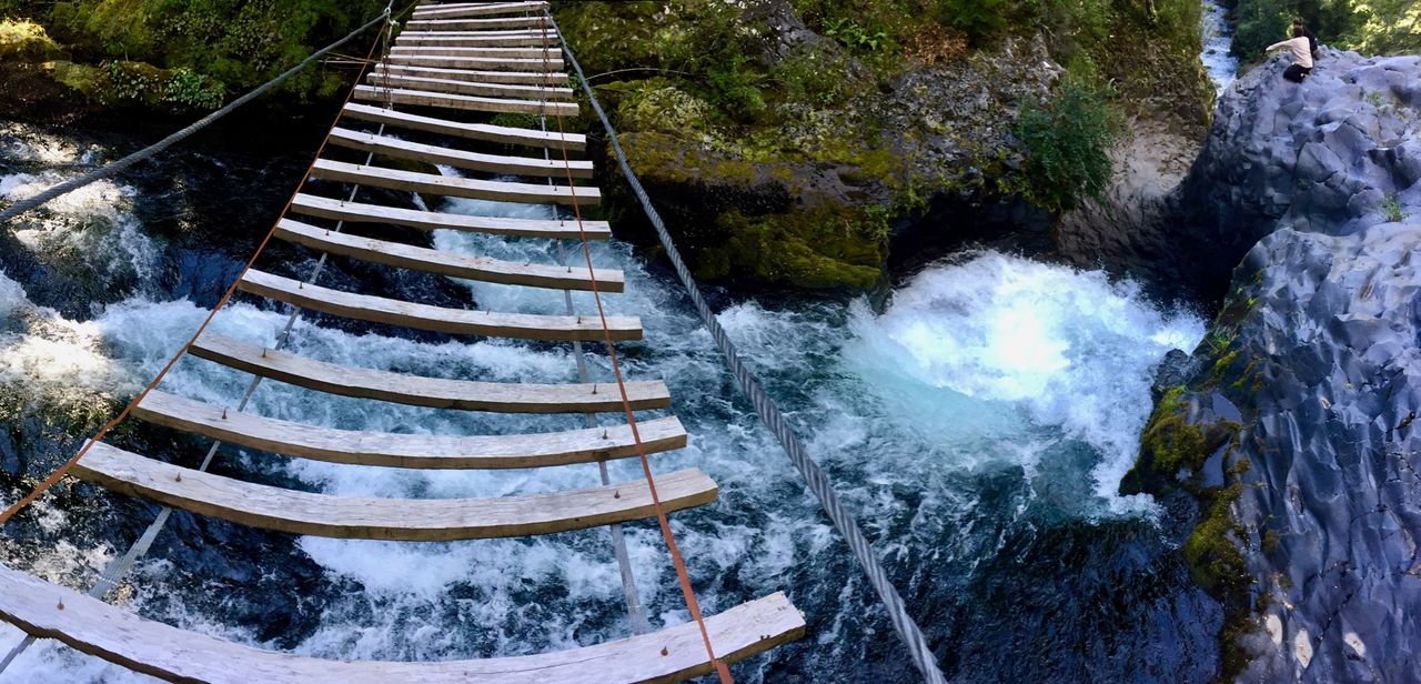 Panoramic from a suspension bridge overlooking a waterfall.