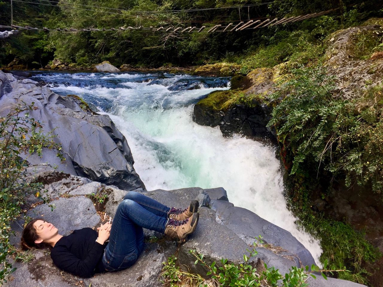 Woman laying near a waterfall.
