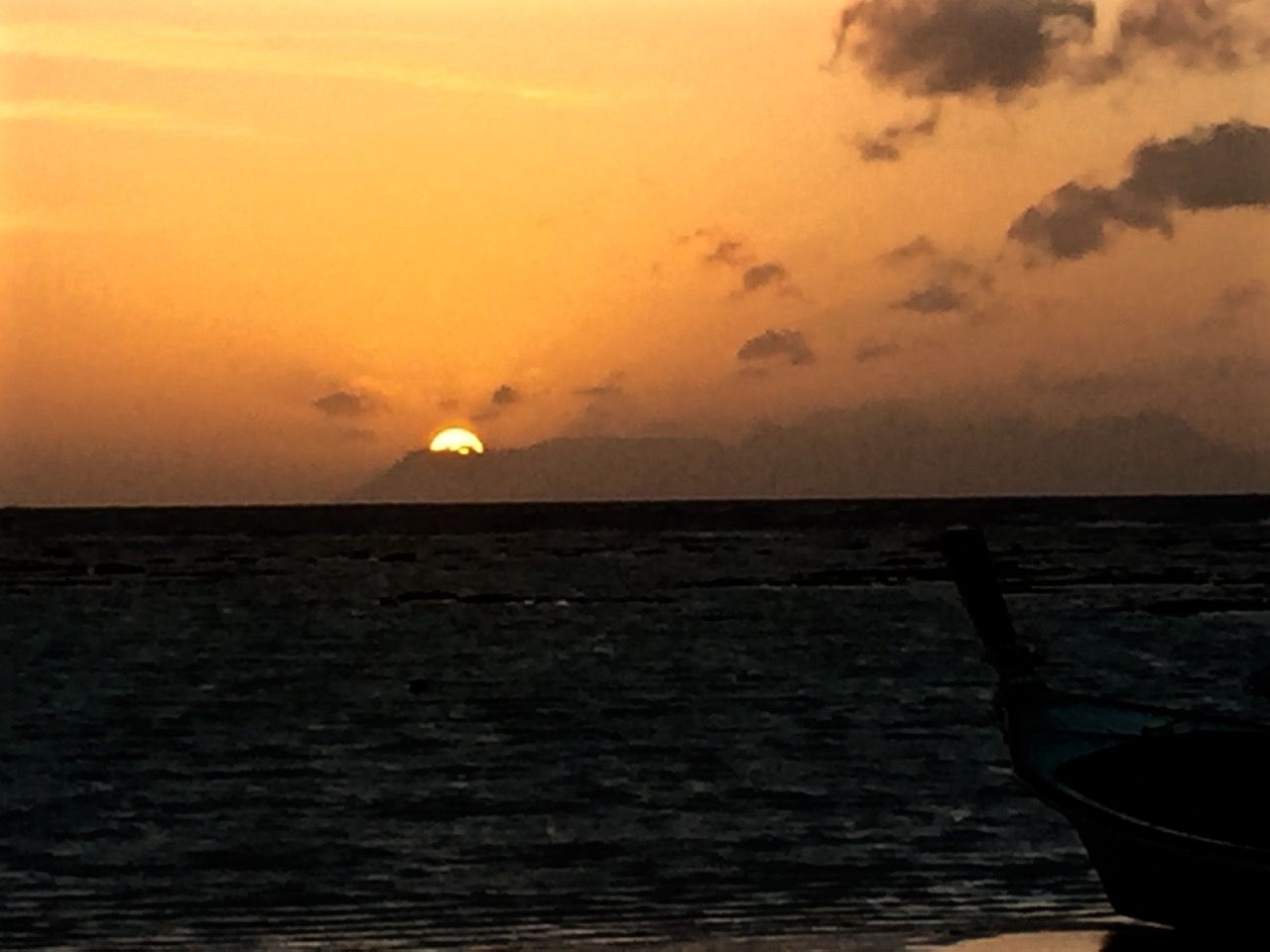 The sun rising from behind a far-away island.