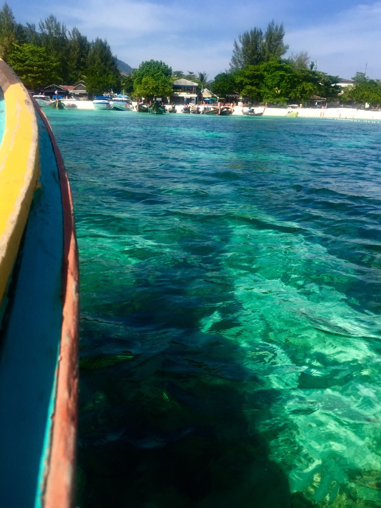 Turquiose, crystal clear water with coral and rocks below a boat.