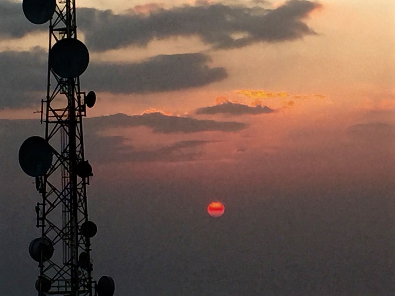 Bright red sun next to a TV tower.