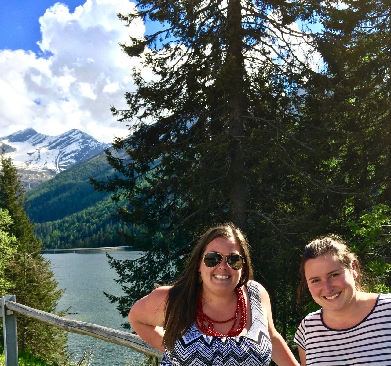 Two women smiling with a lake in the background.