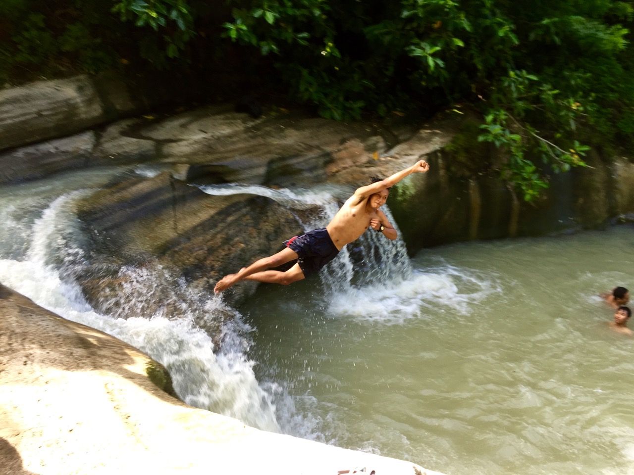 Boy jumping off a rock and posing.