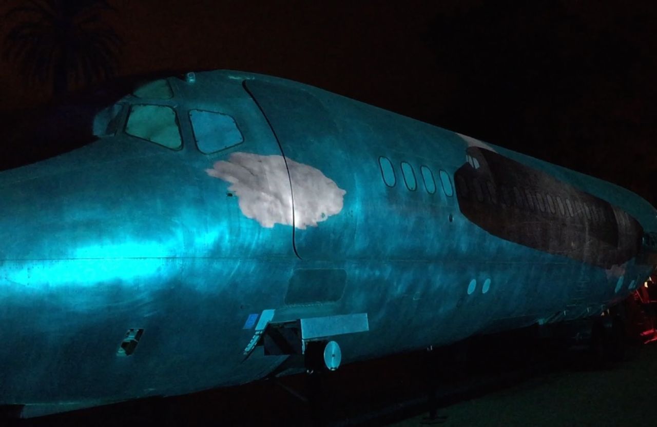 An airplane fuselage lit by projectors.