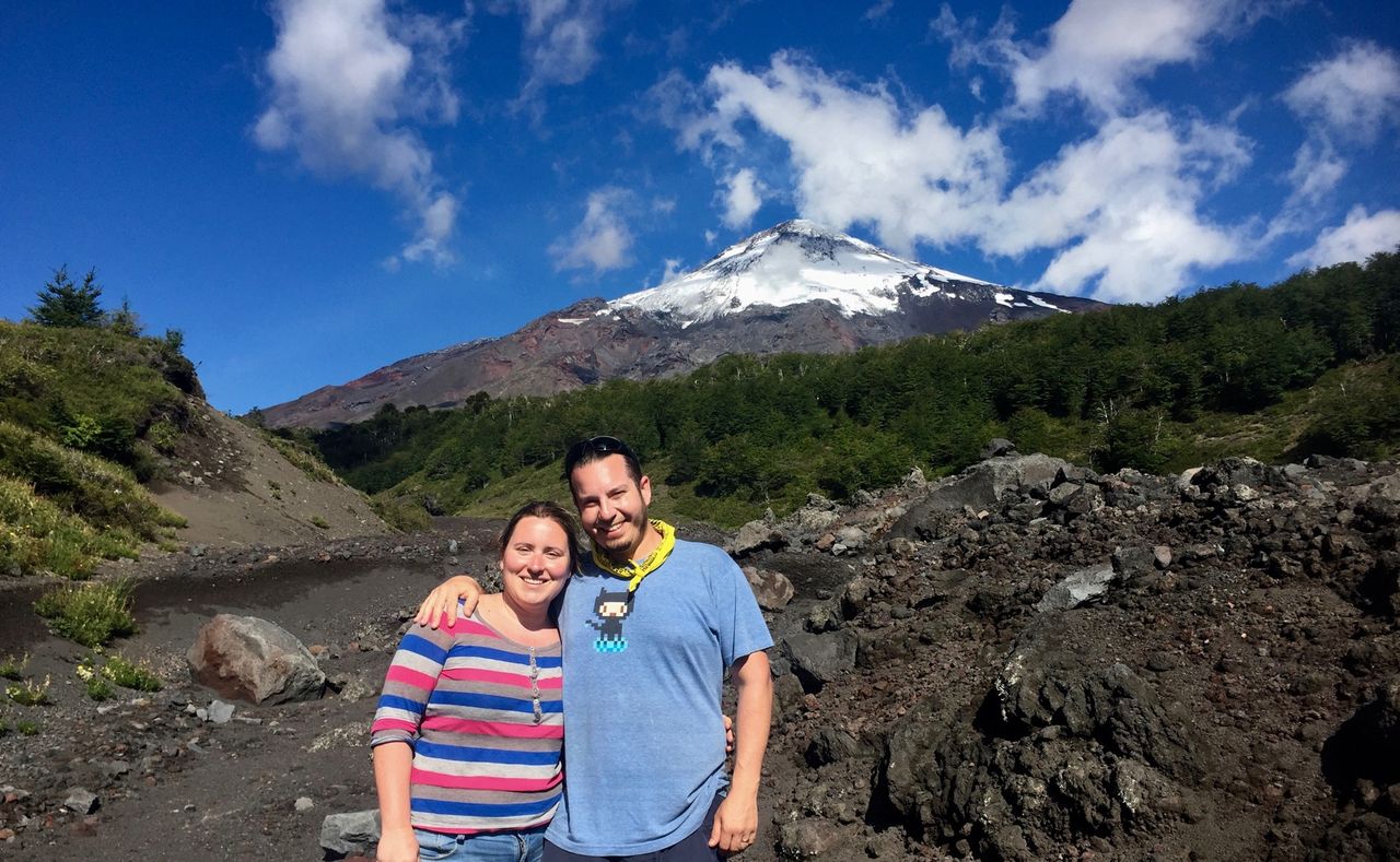 Couple smiling with volcano in background.
