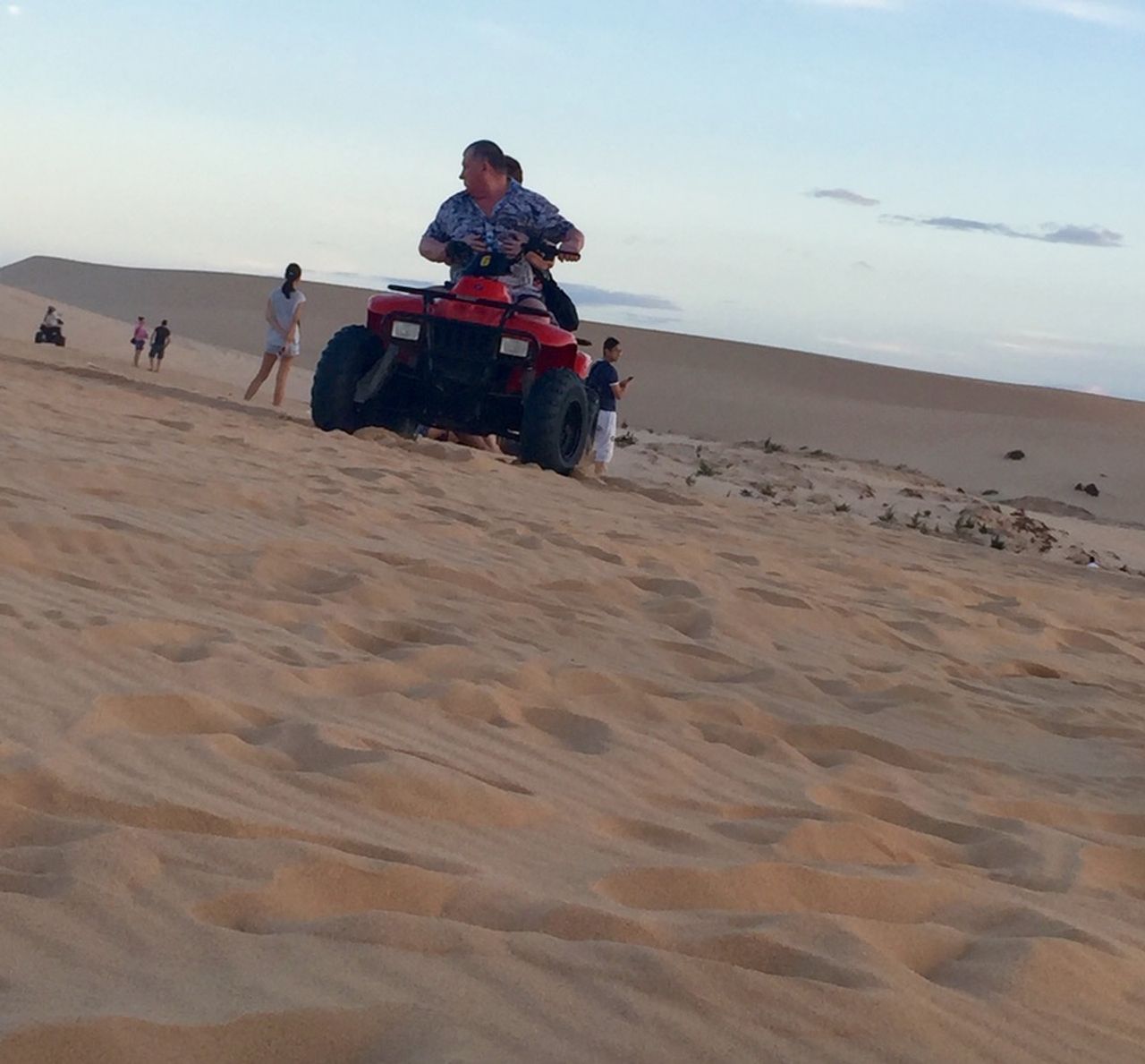 Old couple on a dune buggy in the sand.