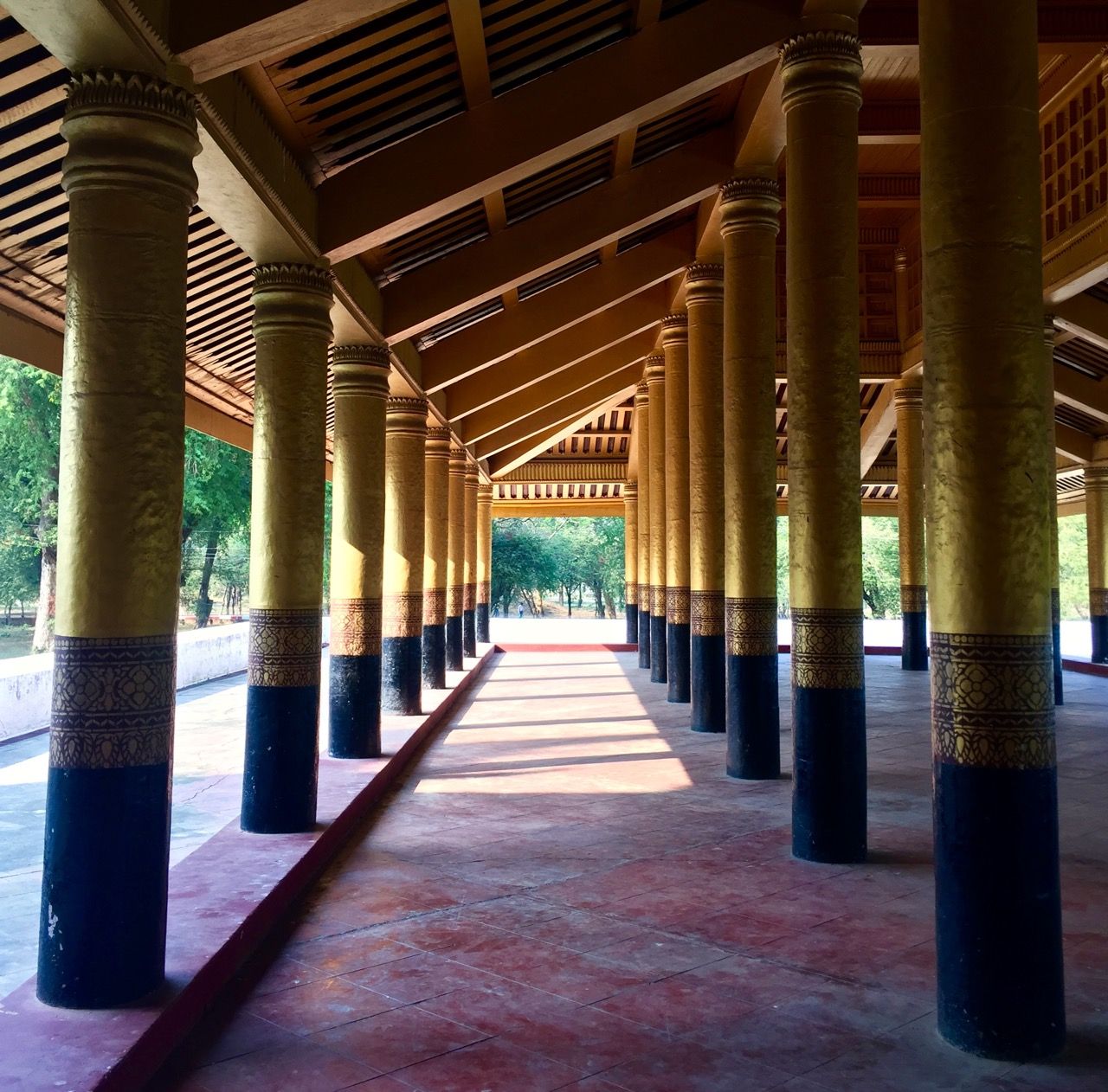 An entryway lined by gold-painted poles.