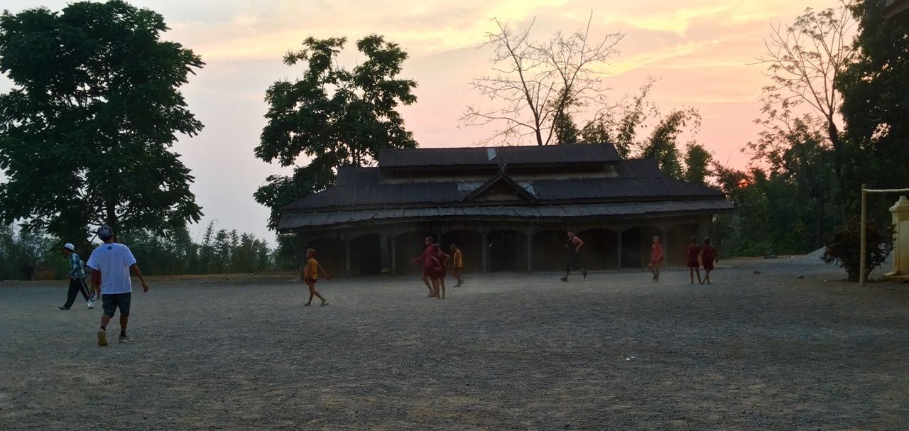Men playing soccer with young monks.