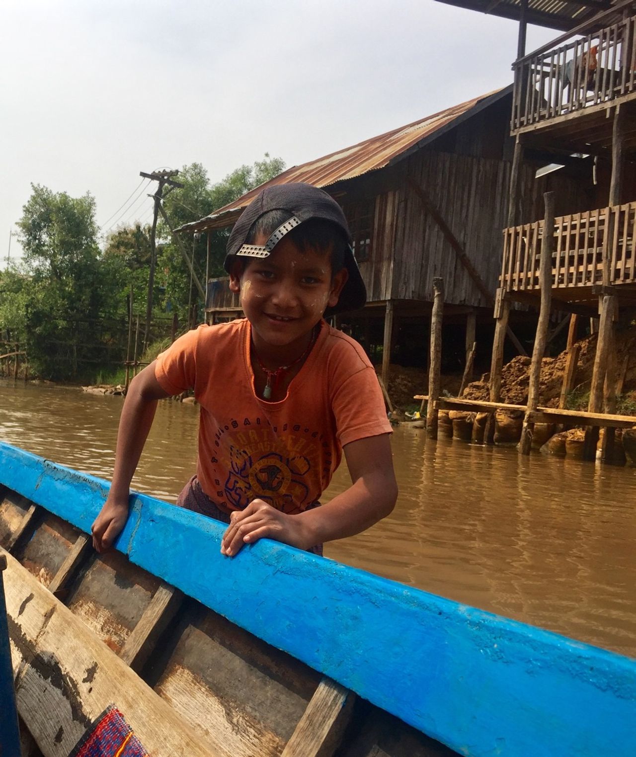 Young boy pushing a boat out of shallow water.