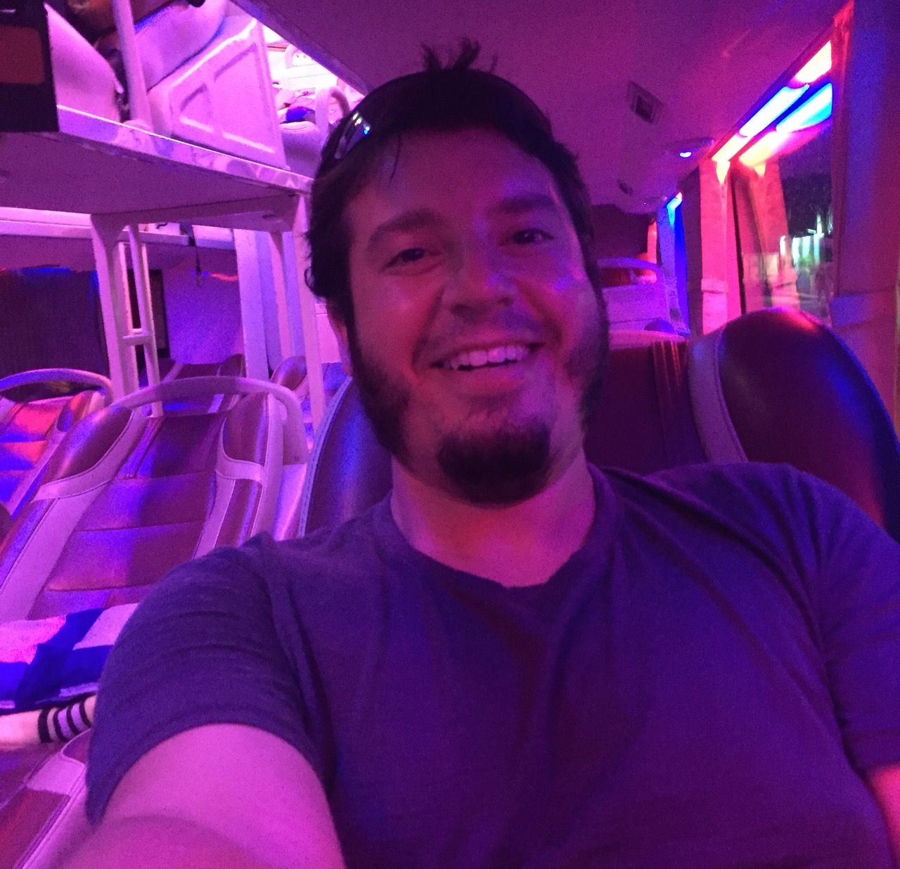 Man smiling inside a lit up night bus.