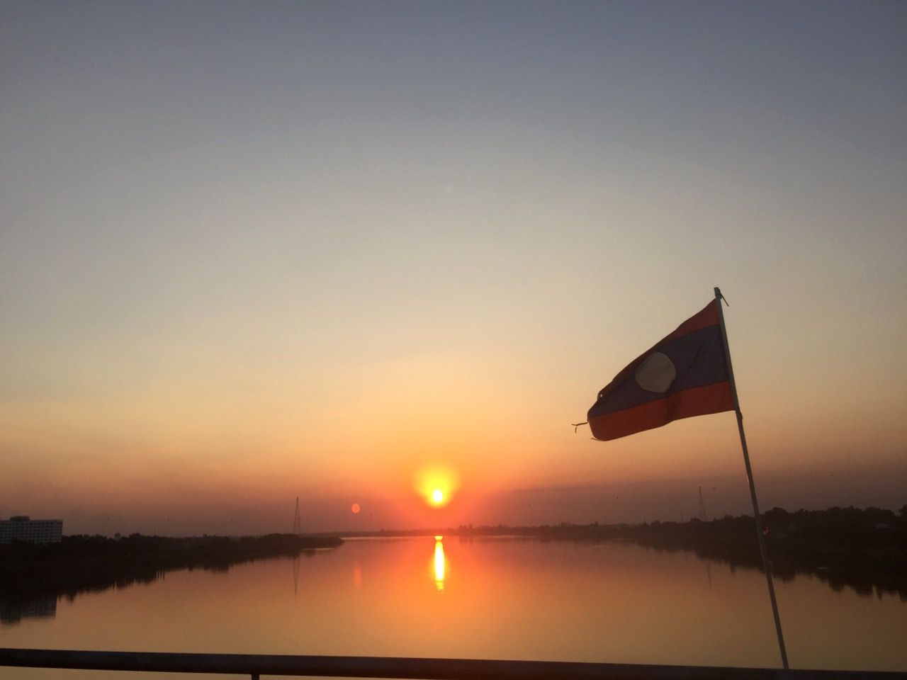 Laos flag with sunset in background.