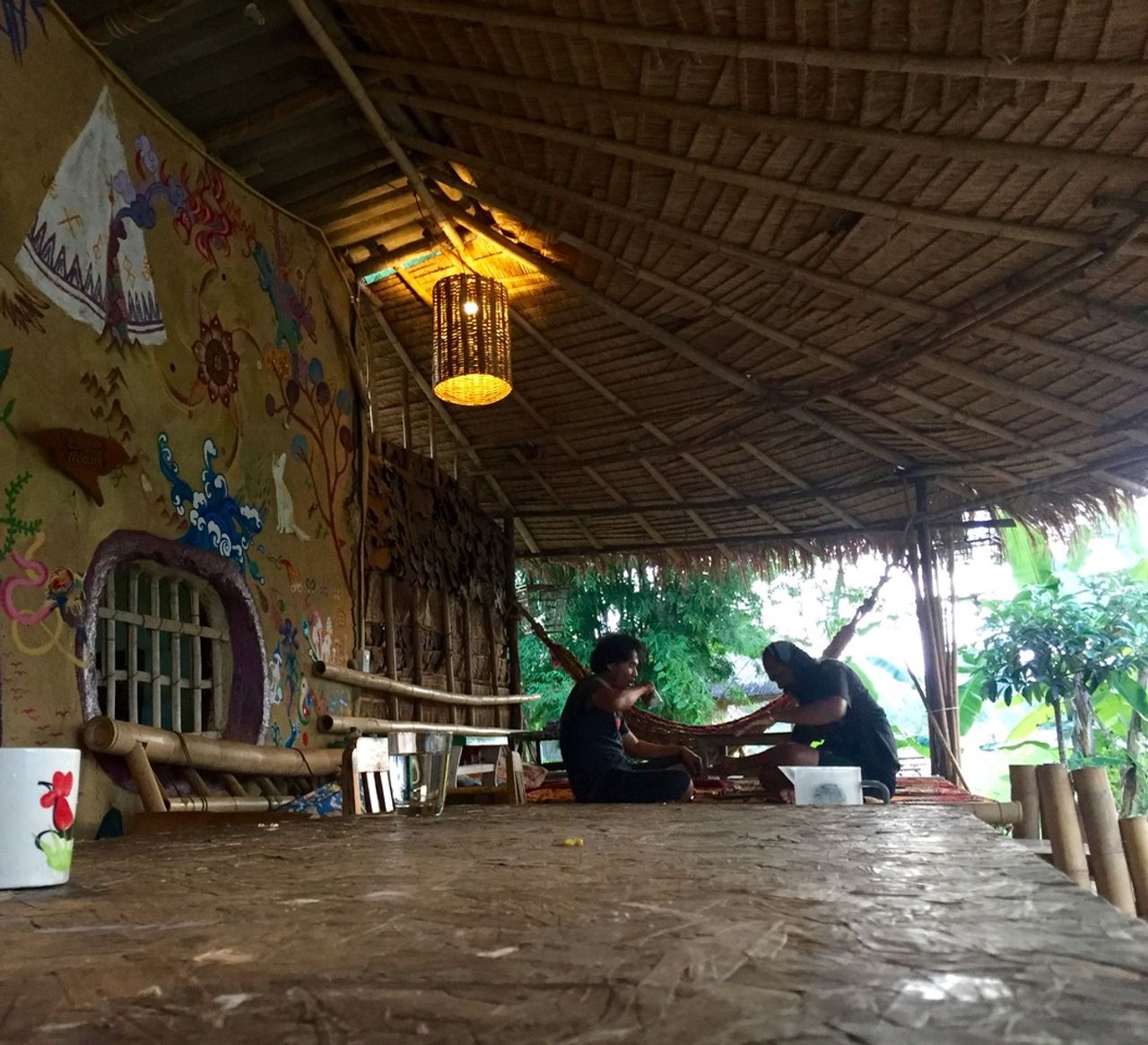 Two people playing music under a hut.