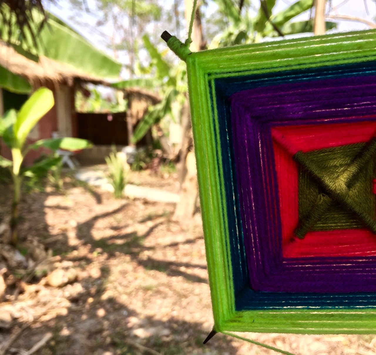 Yarn wind ornament hanging on a bungalow porch.