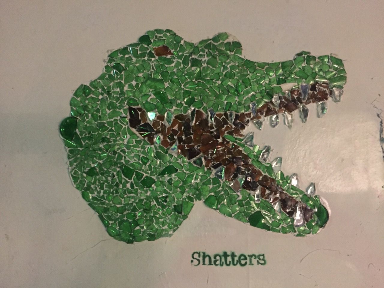 Art depicting an alligator. It has a caption that says "Shatters"