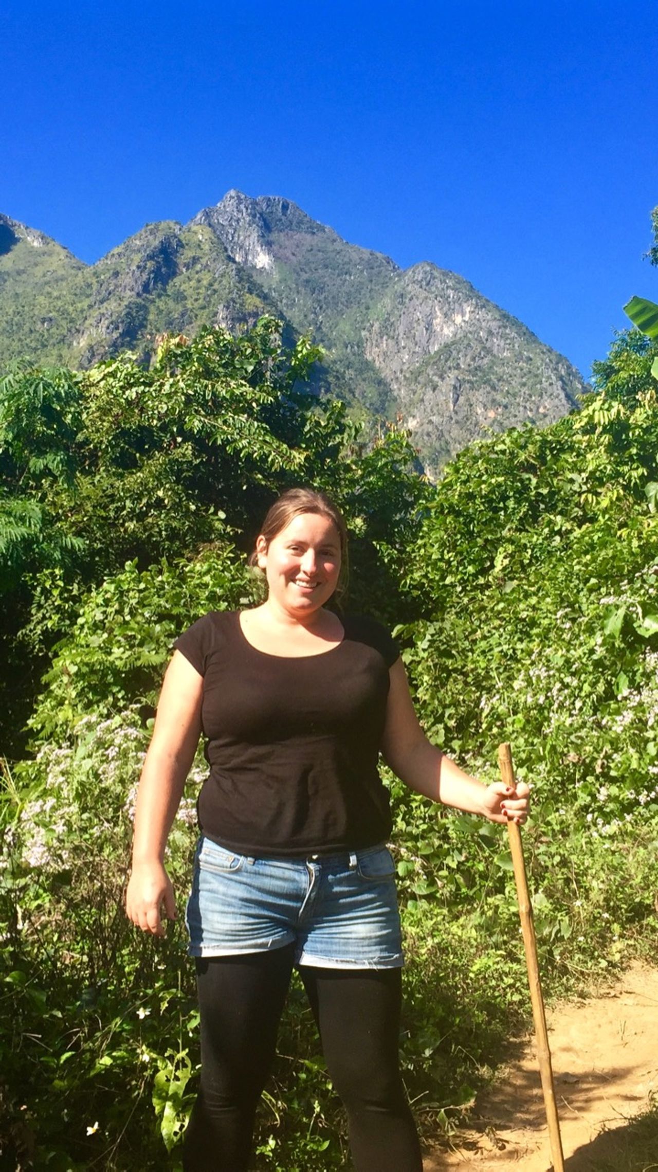 Woman posing for camera with mountains behind her.