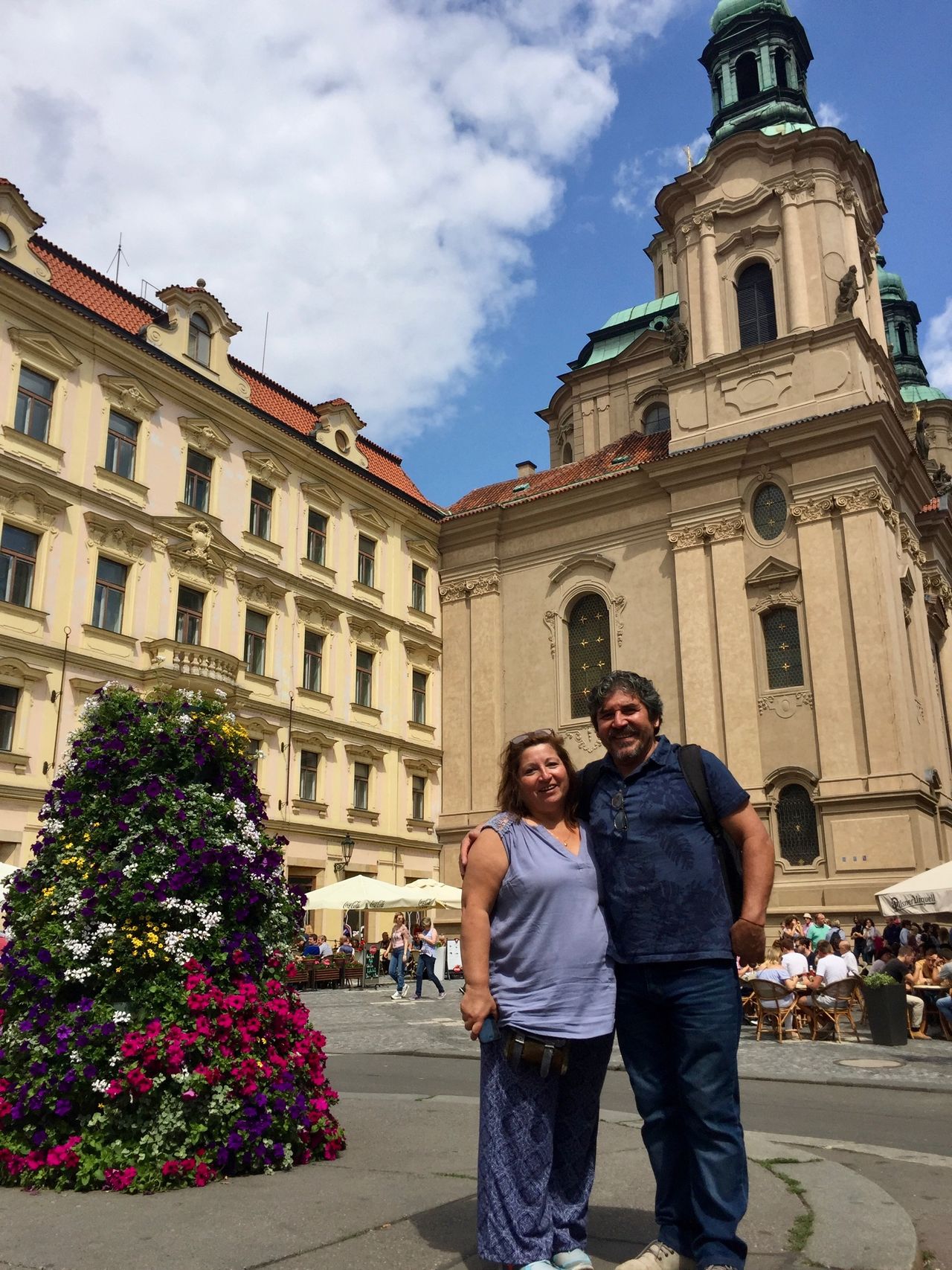 Man and woman standing near flowers and church building.