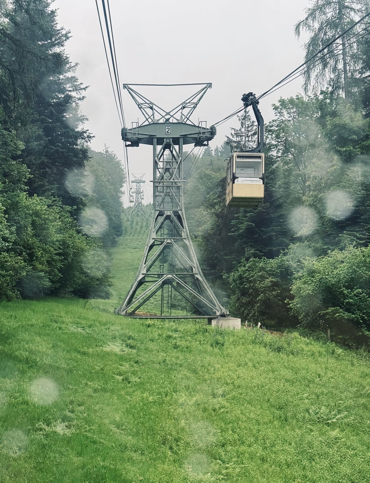 looking up the gondola line from inside a cab through a rain speckled window