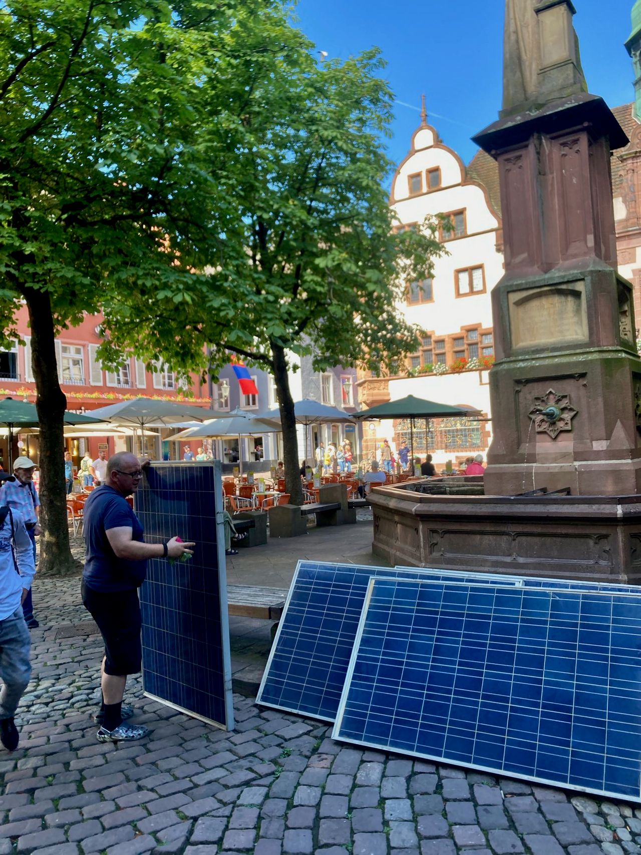 A man stacks solar panels against the fountain in Freiburg's Rathausplatz