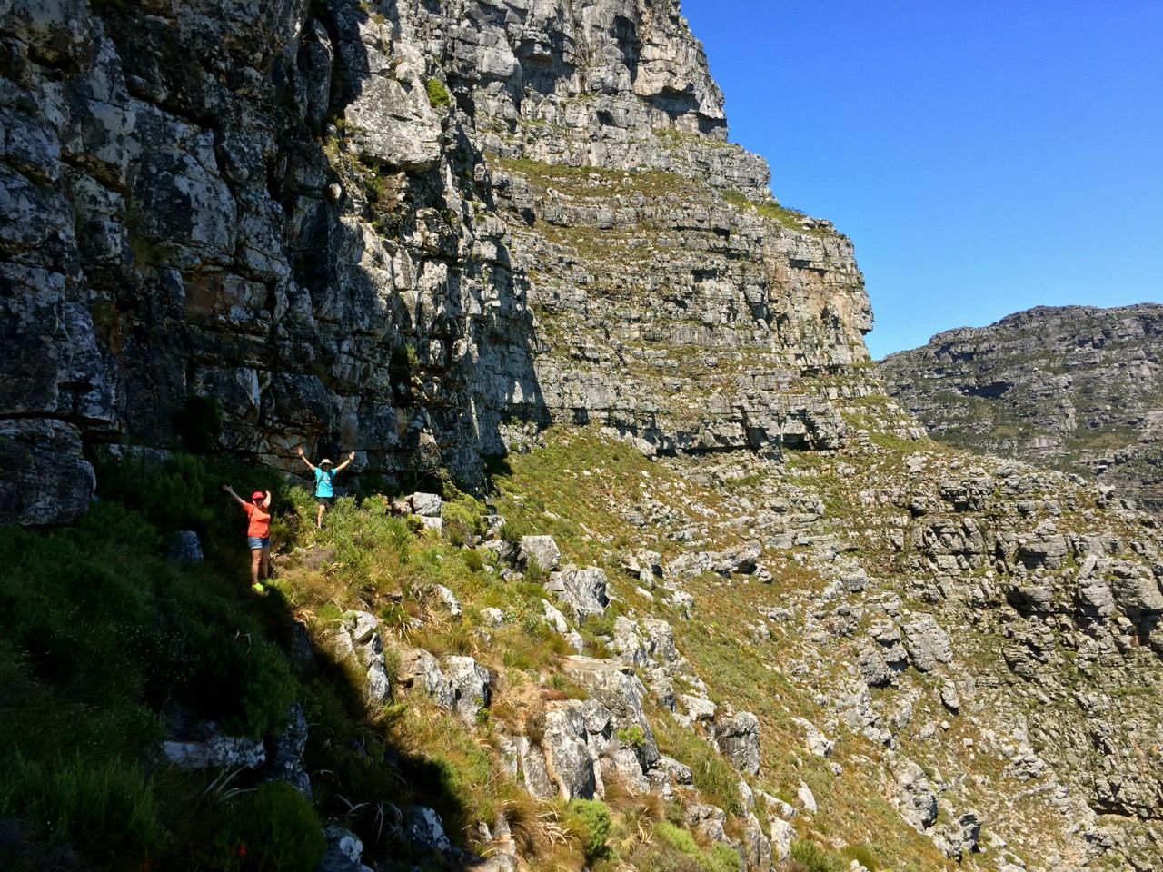 People hiking a vast mountainside.