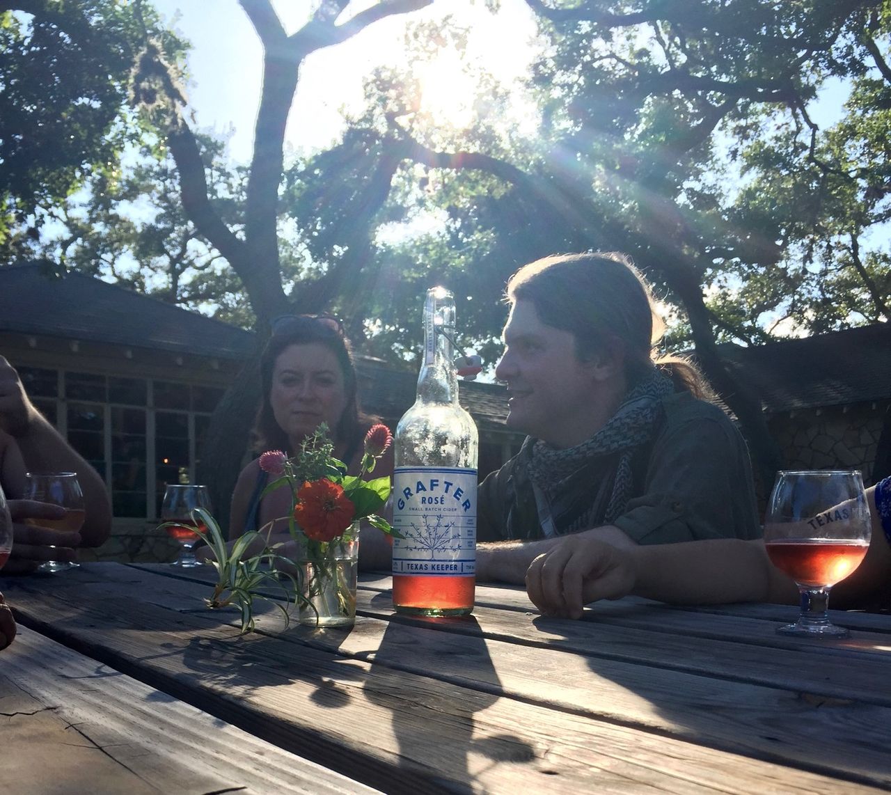 Friends at a table as the sun hangs in the sky.