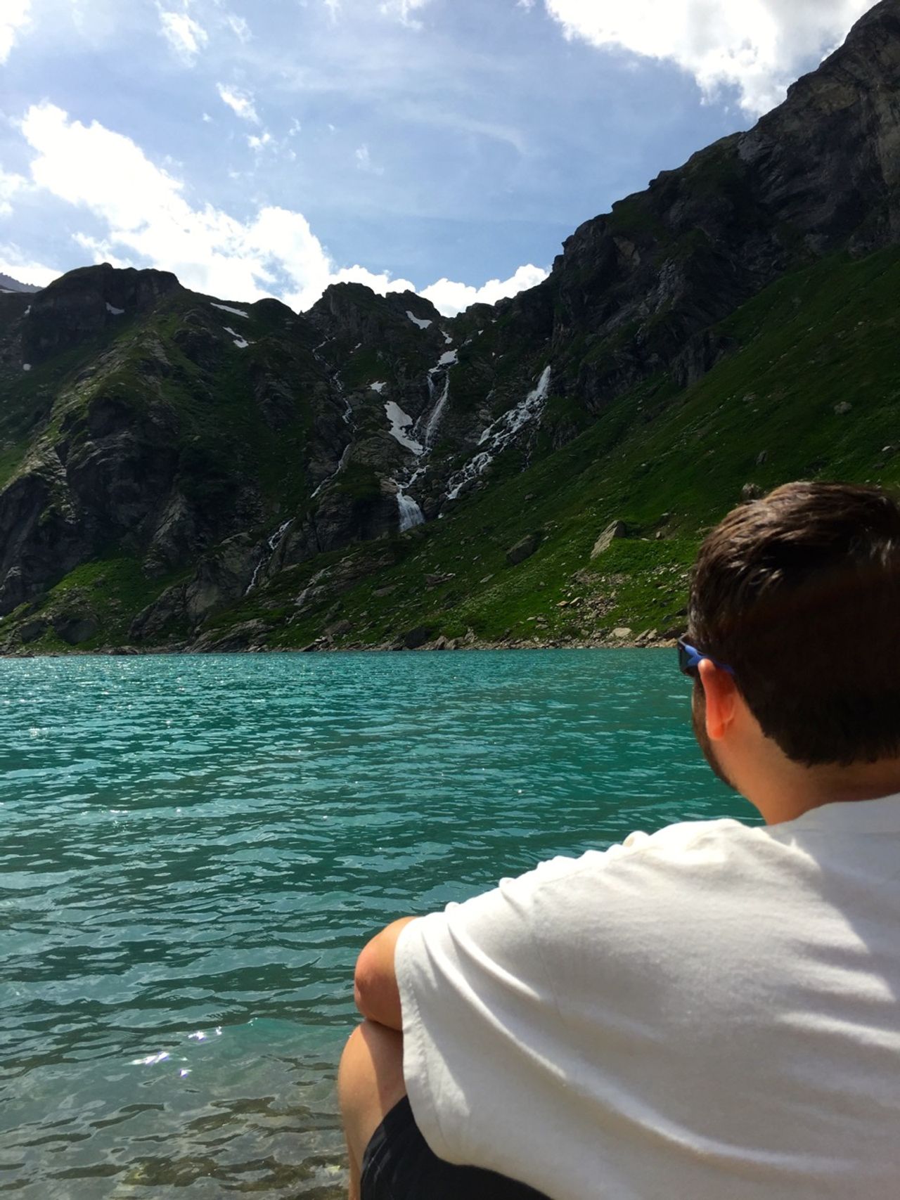 Man overlooking a glacier-fed reservior in the Swiss Alps.