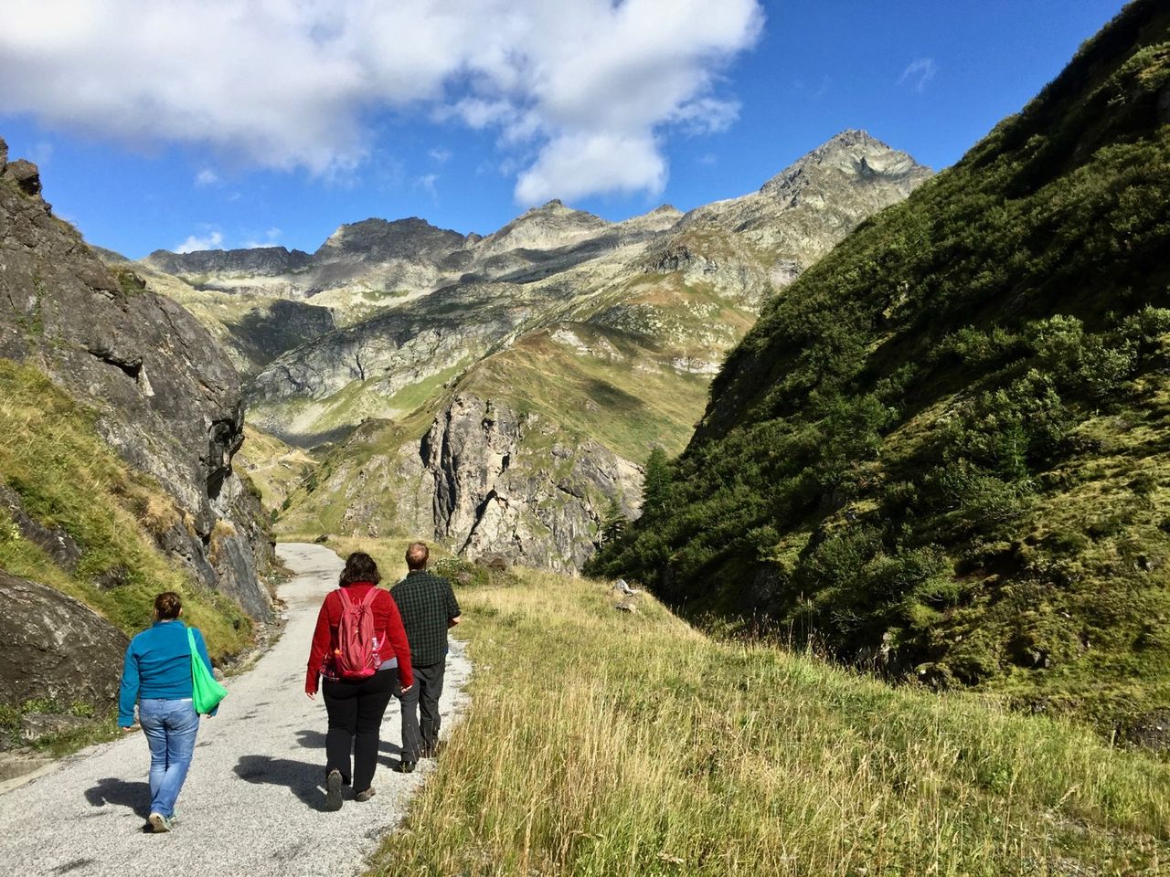 Three people walking along a path with mountains in the background.