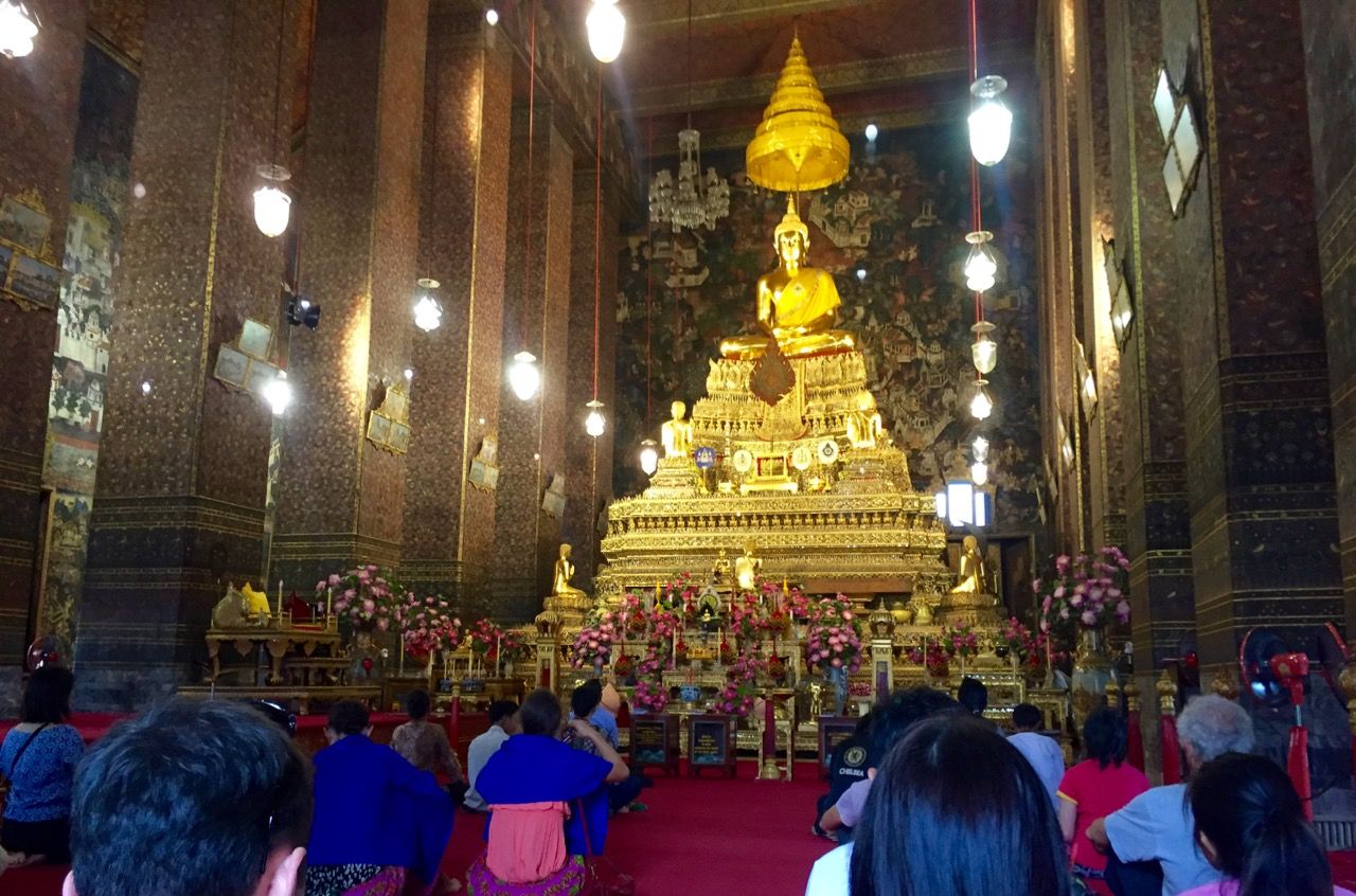 Inside of a temple with a large golden statue of Buddha